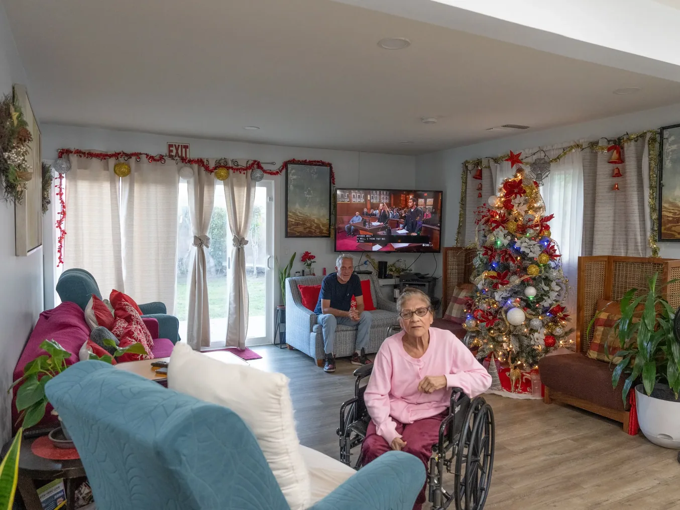 Residents enjoying the holiday-decorated living room with Christmas tree and comfortable seating areas