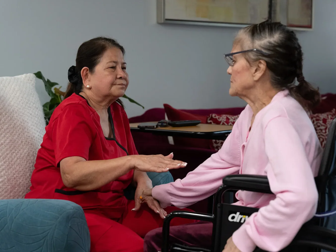 Two senior residents having a conversation together in a comfortable living room setting